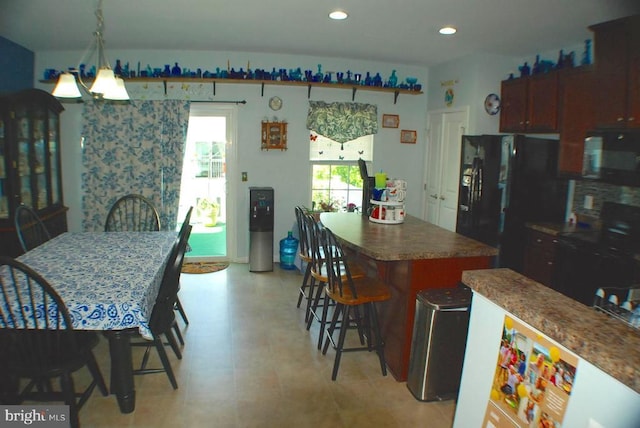  - kitchen featuring black appliances, a center island, a breakfast bar area, recessed lighting, and dark countertops