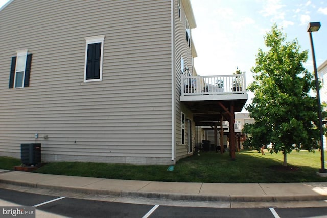  - view of property exterior featuring a lawn, a balcony, and uncovered parking