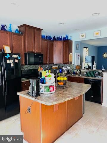  - kitchen featuring black appliances, backsplash, light stone counters, and a peninsula