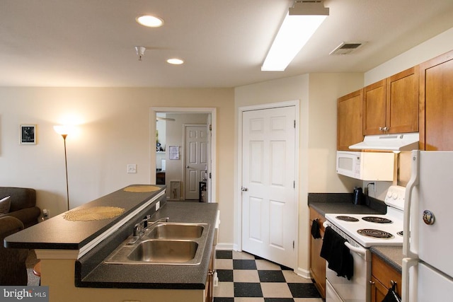 kitchen with white appliances, under cabinet range hood, dark countertops, dark floors, and a center island