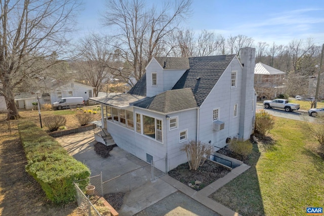view of property exterior featuring a chimney, a yard, roof with shingles, and concrete driveway