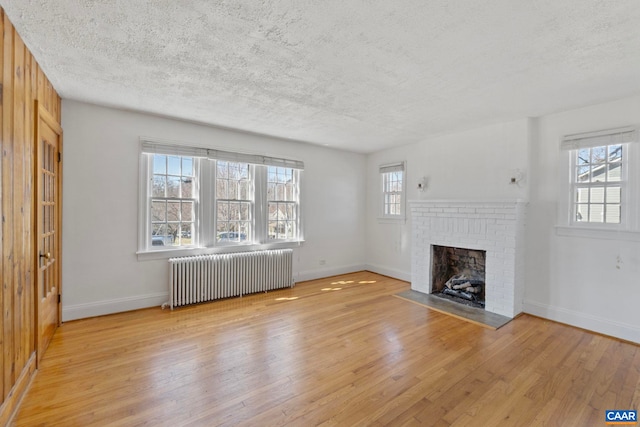 unfurnished living room featuring radiator heating unit, light wood-type flooring, and a textured ceiling