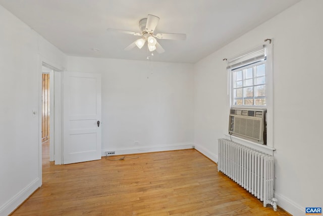 unfurnished room featuring radiator, light wood-type flooring, cooling unit, a ceiling fan, and baseboards