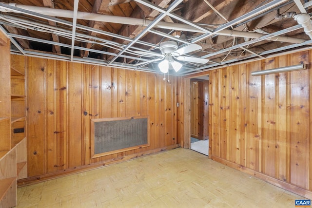 finished below grade area featuring a ceiling fan, wooden walls, and tile patterned floors