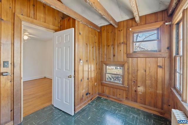 unfurnished room featuring a ceiling fan, radiator heating unit, wood walls, and dark floors
