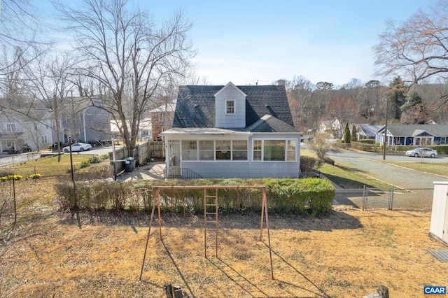 view of front facade featuring a sunroom, roof with shingles, fence, and a residential view