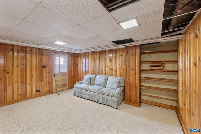 sitting room with wood walls, carpet floors, and a drop ceiling