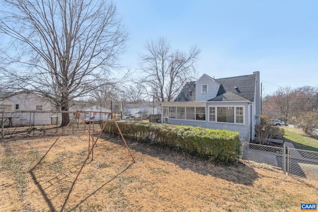 rear view of property with a fenced backyard and a sunroom