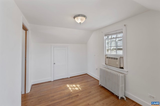 bonus room with lofted ceiling, baseboards, radiator, cooling unit, and light wood finished floors