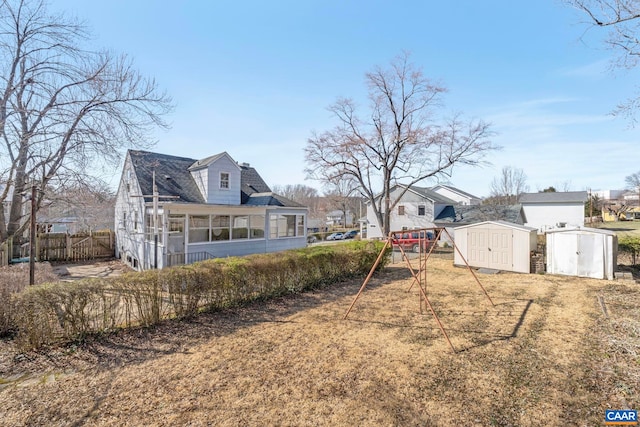 view of yard featuring fence, a storage shed, a sunroom, and an outdoor structure