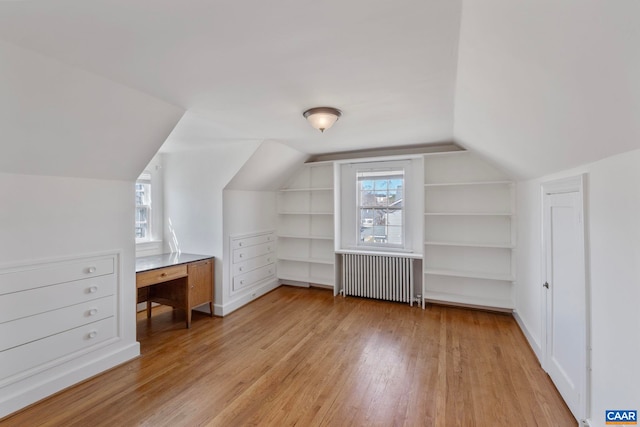 bonus room featuring lofted ceiling, radiator, wood finished floors, and built in features