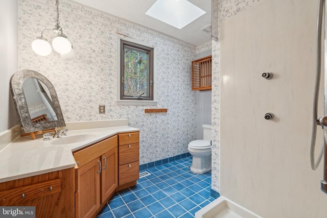 bathroom with a skylight, wallpapered walls, toilet, tile patterned floors, and vanity