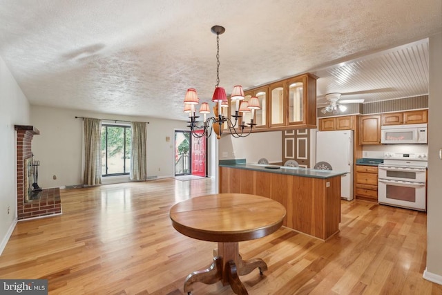 kitchen featuring white appliances, a textured ceiling, a peninsula, light wood finished floors, and a chandelier