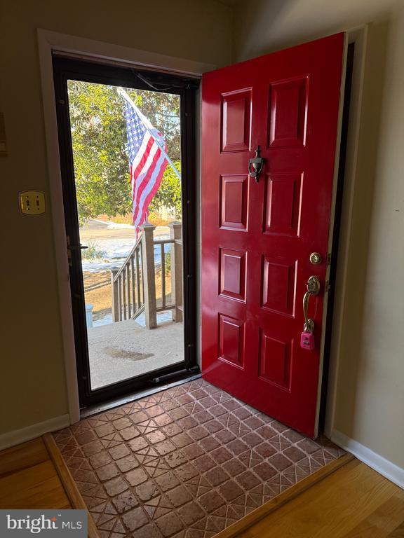 foyer with dark wood-style flooring and baseboards