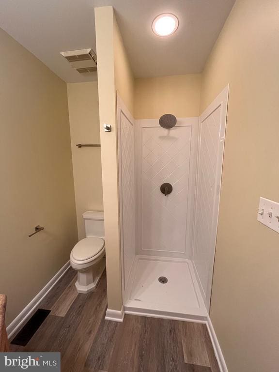 full bathroom with wood finished floors, walk in shower, toilet, and baseboards