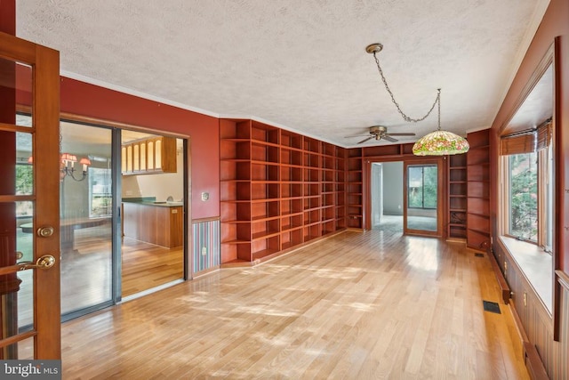 spare room with wood finished floors, a textured ceiling, built in shelves, ceiling fan, and ornamental molding