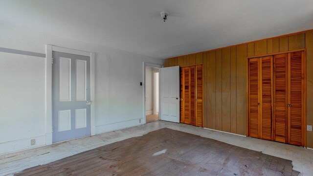506 Williams Ave, Shenandoah, VA 22849 - unfurnished bedroom with wooden walls, wood finished floors, and two closets