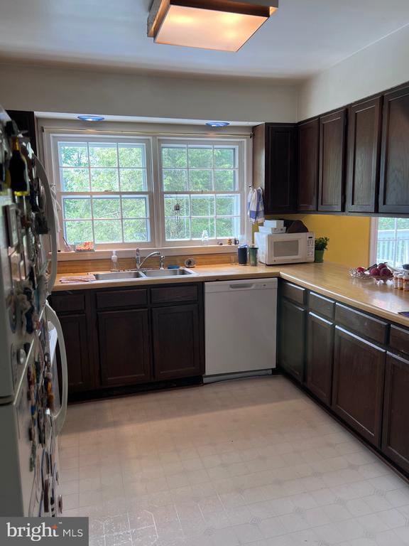  - kitchen featuring white appliances, dark brown cabinetry, light countertops, and light floors
