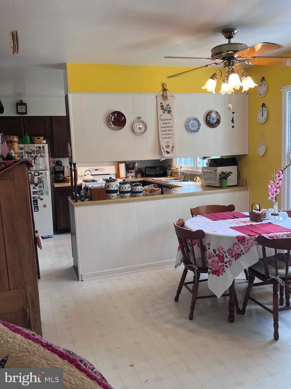  - kitchen with freestanding refrigerator, ceiling fan, light flooring, and a peninsula