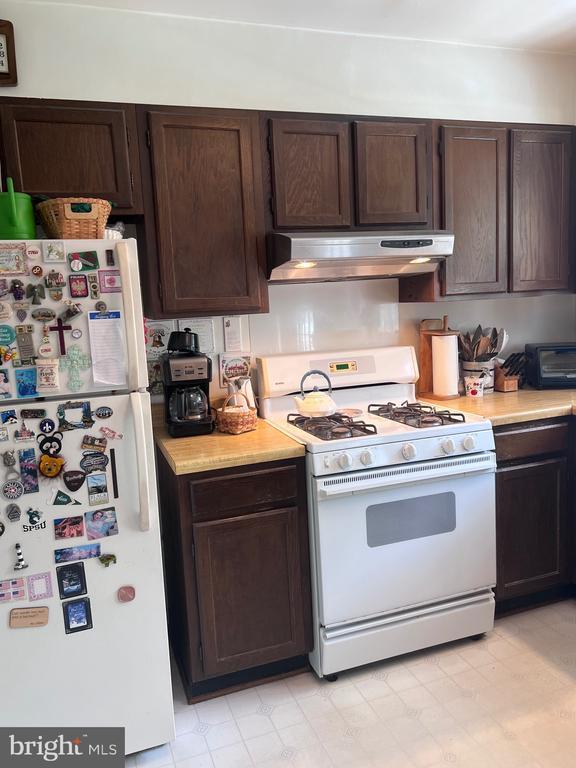  - kitchen with white appliances, under cabinet range hood, dark brown cabinets, and light countertops
