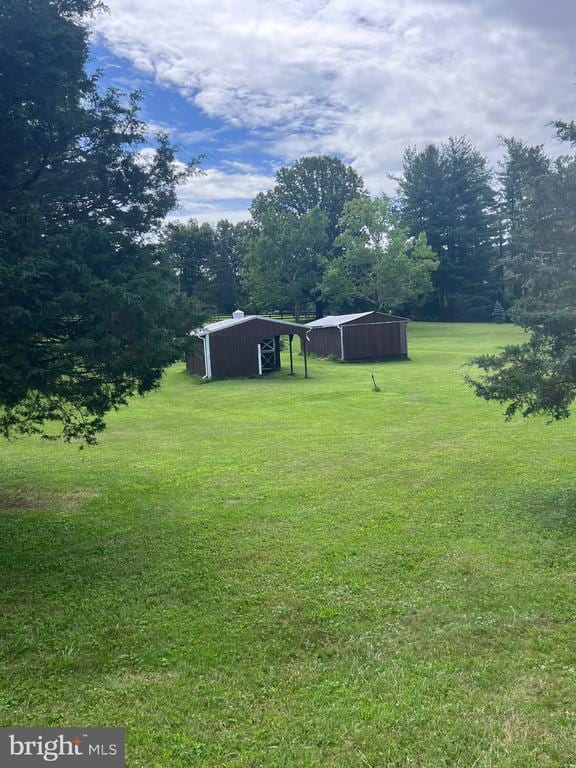  - view of grassy yard with a pole building, an outdoor structure, and a carport