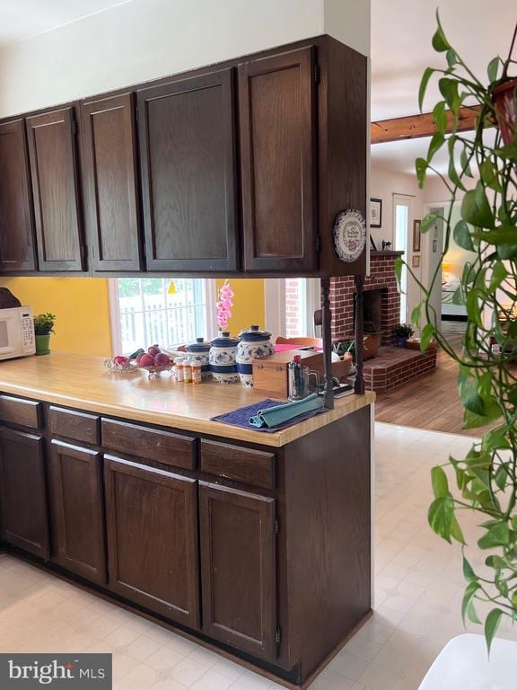  - kitchen with white microwave, dark brown cabinets, and healthy amount of natural light