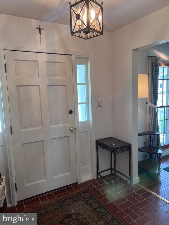  - foyer entrance featuring a chandelier and brick patterned flooring