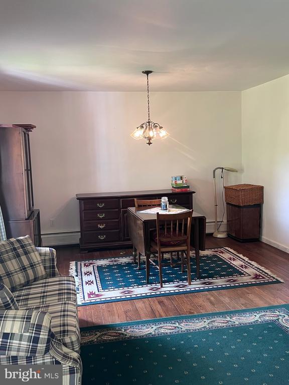  - dining space with wood finished floors and a baseboard heating unit