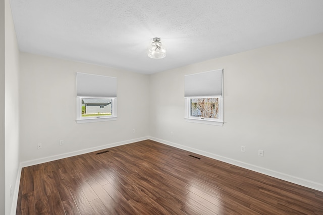 unfurnished room featuring baseboards, wood finished floors, and a textured ceiling