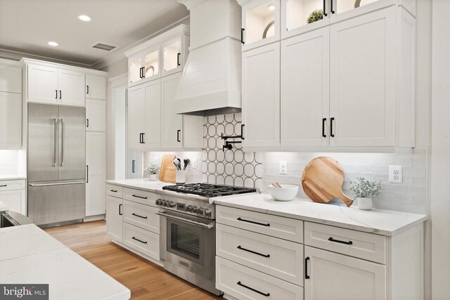  - kitchen featuring high quality appliances, custom exhaust hood, white cabinets, light stone counters, and recessed lighting