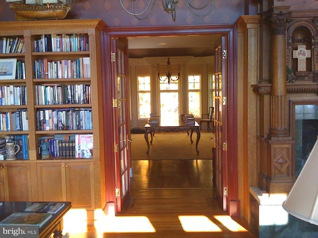  - hall with a chandelier, wallpapered walls, and wood finished floors