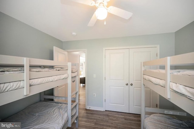 bedroom with dark wood-style floors, a closet, baseboards, and a ceiling fan