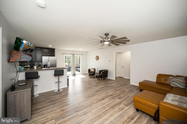 living area with light wood-style flooring, a ceiling fan, baseboards, and recessed lighting