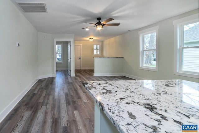 interior space featuring baseboards, visible vents, dark wood-style flooring, and a ceiling fan