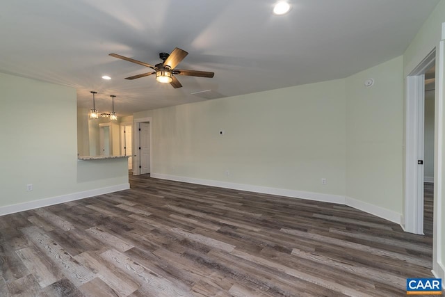 interior space featuring ceiling fan with notable chandelier, dark wood-type flooring, baseboards, and recessed lighting
