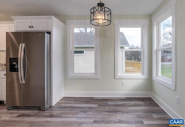 unfurnished dining area with dark wood-style flooring, an inviting chandelier, and plenty of natural light