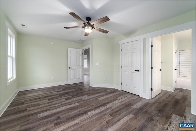 unfurnished bedroom featuring baseboards, multiple windows, visible vents, and dark wood-style flooring