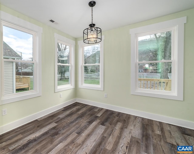 unfurnished dining area with a chandelier, baseboards, dark wood-style floors, and visible vents