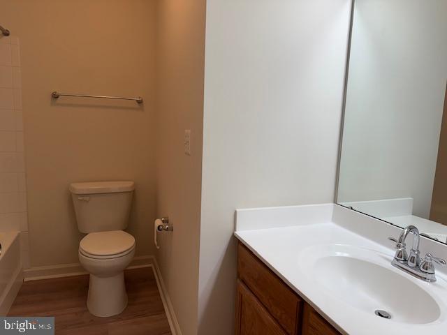 bathroom with wood finished floors, toilet, vanity, and baseboards