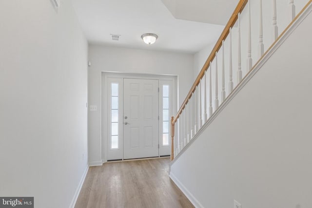 foyer entrance with stairs, baseboards, and wood finished floors
