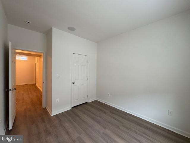 unfurnished bedroom with dark wood-type flooring and baseboards
