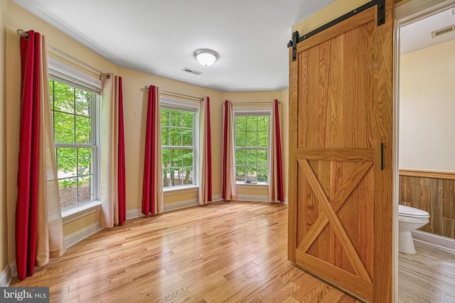 188 Byrd Point Ln, Louisa, VA 23093 - spare room with a barn door, light wood finished floors, and a wainscoted wall