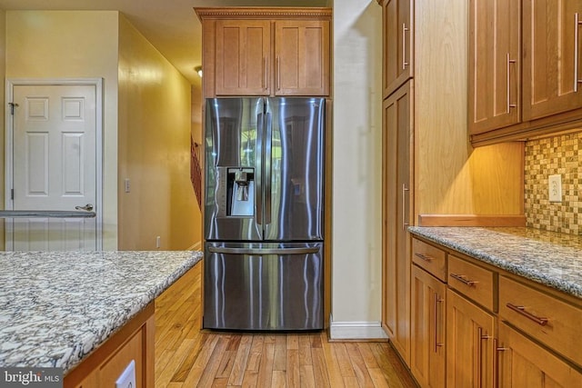 188 Byrd Point Ln, Louisa, VA 23093 - kitchen featuring stainless steel fridge with ice dispenser, backsplash, light wood-type flooring, brown cabinetry, and light stone countertops