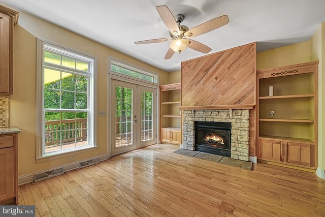 188 Byrd Point Ln, Louisa, VA 23093 - unfurnished living room with light wood finished floors, a ceiling fan, a fireplace, and french doors