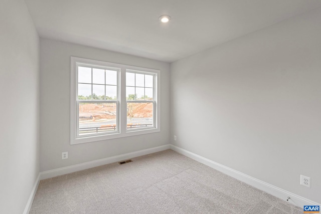 spare room with baseboards, recessed lighting, light carpet, and visible vents