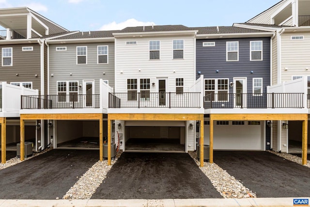 back of house featuring central air condition unit, an attached garage, and driveway