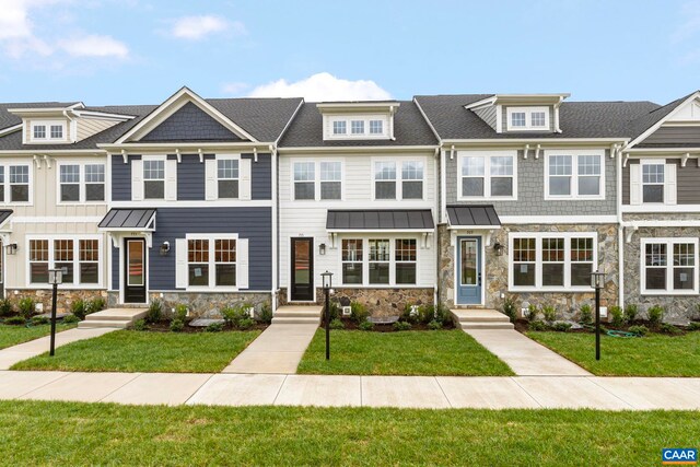 multi unit property featuring a front lawn, a standing seam roof, and stone siding