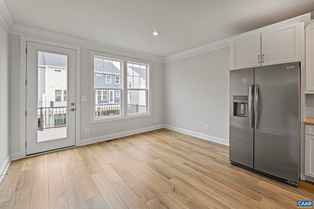 kitchen with light wood-style floors, stainless steel fridge, baseboards, and ornamental molding