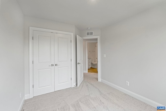 unfurnished bedroom featuring baseboards, carpet flooring, a closet, and visible vents