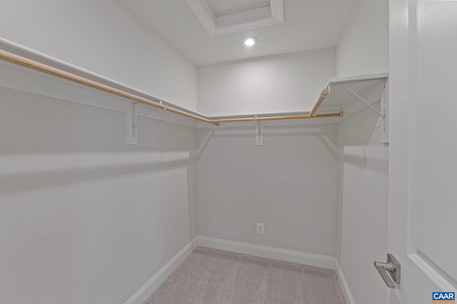spacious closet with light colored carpet and attic access
